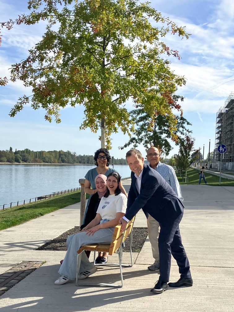 Auf der Bank am Rheinufer am Yilmaz-Atalay-Ufer: (v.l.n.r.) Sima Hosseini, Vorsitzende des Beirats für Migration und Integration der Landeshauptstadt Mainz; Dr. Gülsüm Günay, Bildungsforum Mainz e.V.; Ciara Widmann, Leiterin CSR und Nachhaltigkeit 1. FSV Mainz 05; Behrouz Asadi, Aktivist und Träger des Bundesverdienstkreuzes; Nino Haase, Oberbürgermeister der Landeshauptstadt Mainz