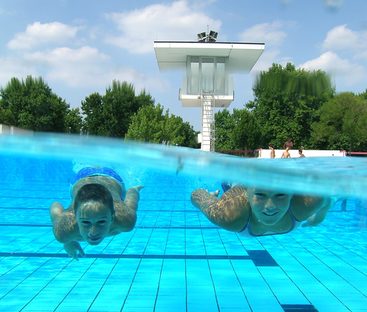 Zwei Kinder tauchen im Freibad, Unterwasseraufnahme