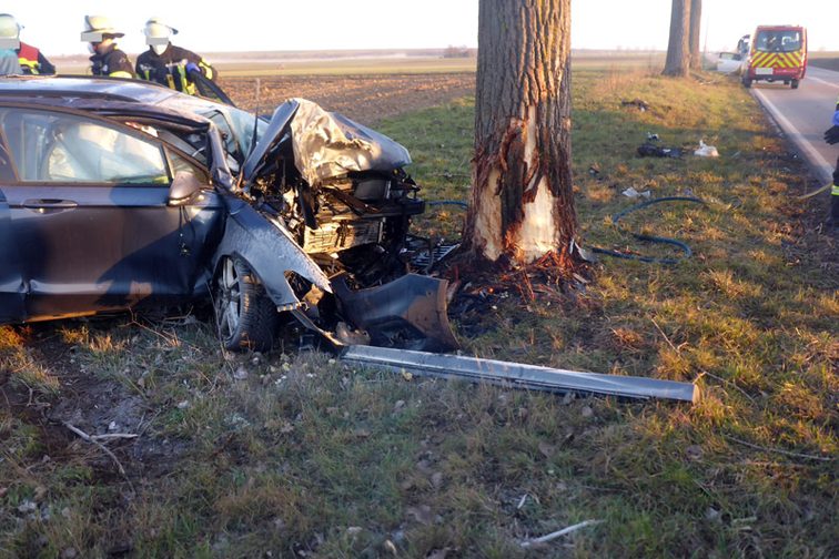 Stark beschädigtes Unfallfahrzeug neben dem Baum, mit dem es kollidierte.