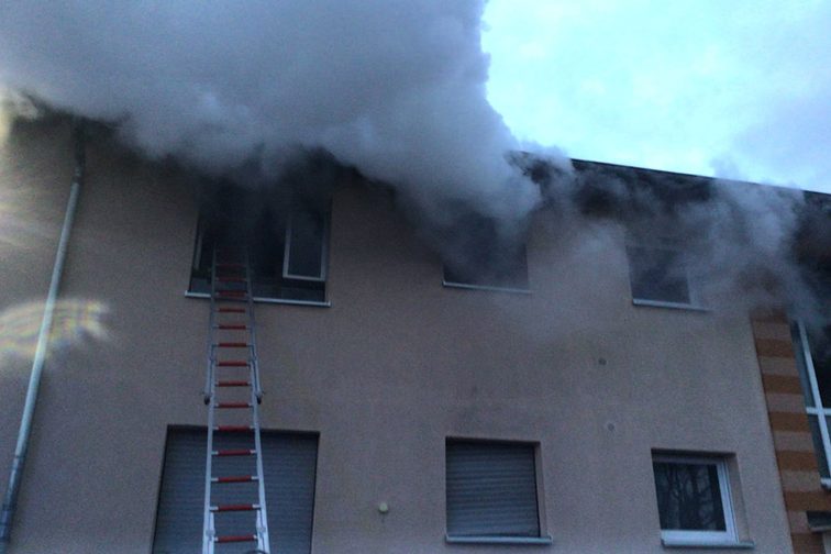 Rauch dringt aus einem Fenster im ersten Stock aus.