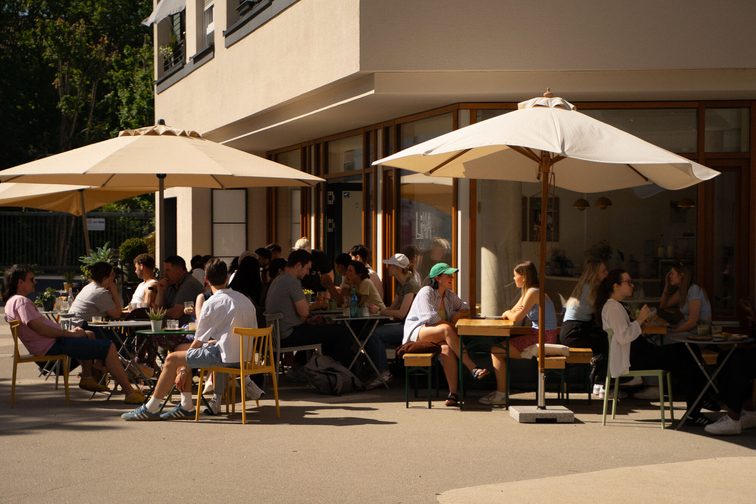 Menschen sitzen unter Sonnenschirmen im Café