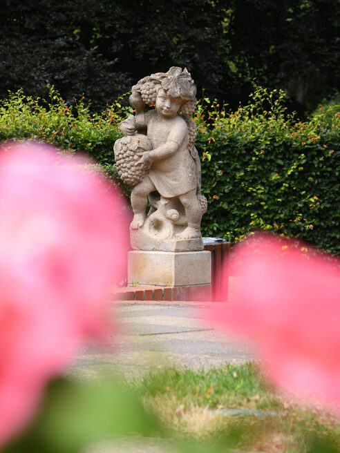 Eine Statue mit Blütenblättern im Vordergrund des Bildes
