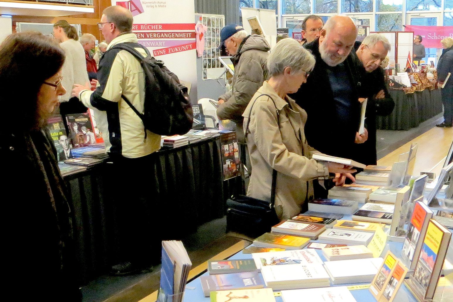 Menschen stöbern auf der Mainzer Büchermesse, an verschiedenen Ständen nach Büchern