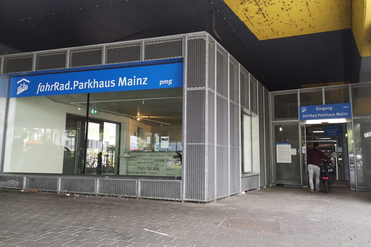 Bild vom Eingang des fahrRad.Parkhaus Mainz am HBF West. Mann mit Lastenrad geht durch den Eingang.