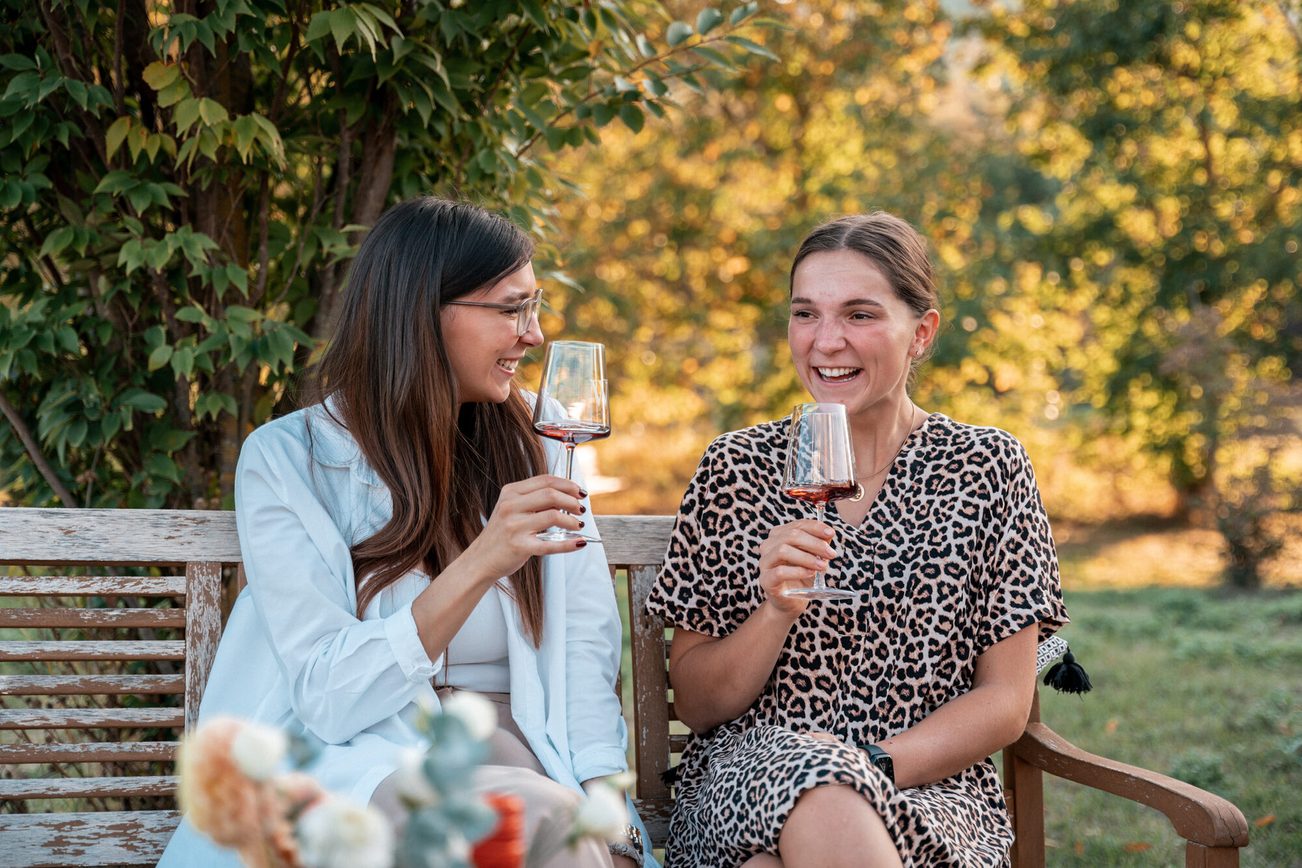 Deux femmes sont assises sur un banc avec un verre de vin.