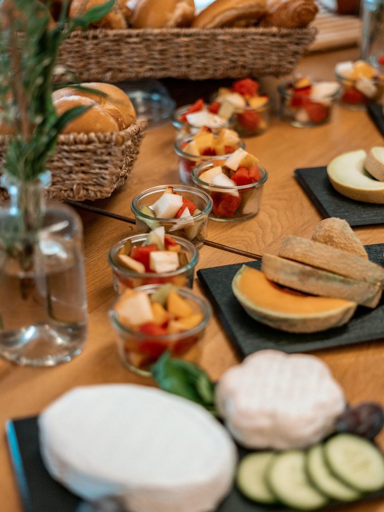 Fromage, concombres, tomates, petits pains et bien plus encore sur une même table.