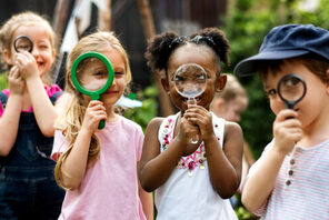 Vier Kinder, die neugierig durch Lupen schauen © AdobeStock rawpixel