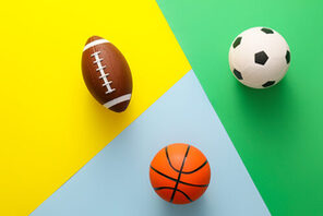 Ein Fußball, Football und Basketball auf buntem Untergrund © AdobeStock Shot