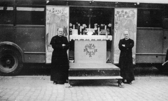 Seelsorge für Heimatvertriebene: Missionspriester vor dem geöffneten Altar des „Magnificat“-Kapellenwagen auf dem Platz vor der evangelischen Kirche in Hungen, Fronleichnam 1953.