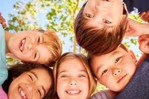 Lachende Kinder stehen Kopf an Kopf im Kreis © AdobeStock