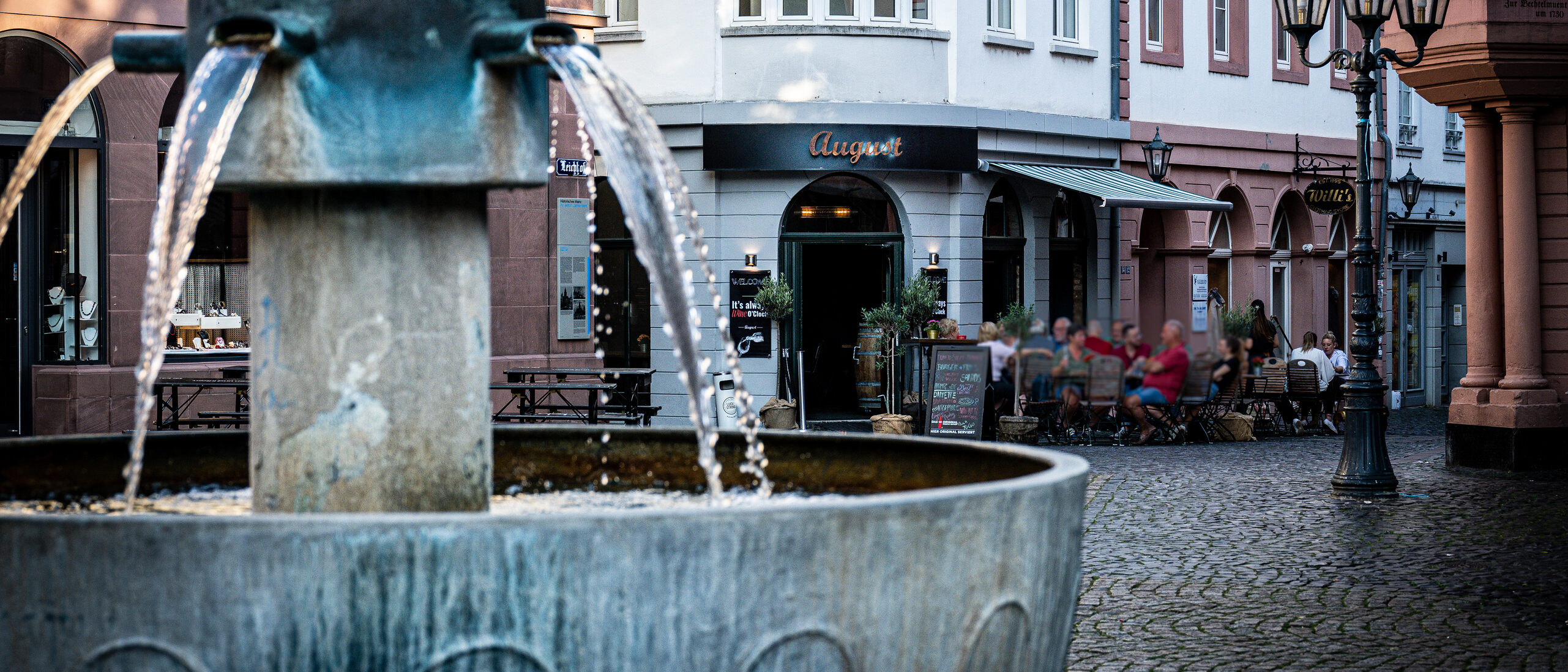 Leichhof fountain in the old town, with a restaurant and stores in the background