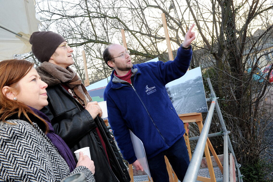 Ein Mitarbeiter erläutert Besuchern die Pläne zum Archäologischen Zentrum