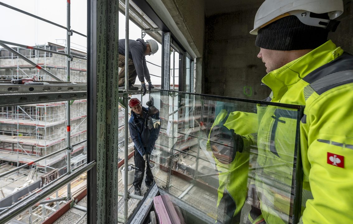 Drei Bauarbeiter mit einer Fensterscheibe.