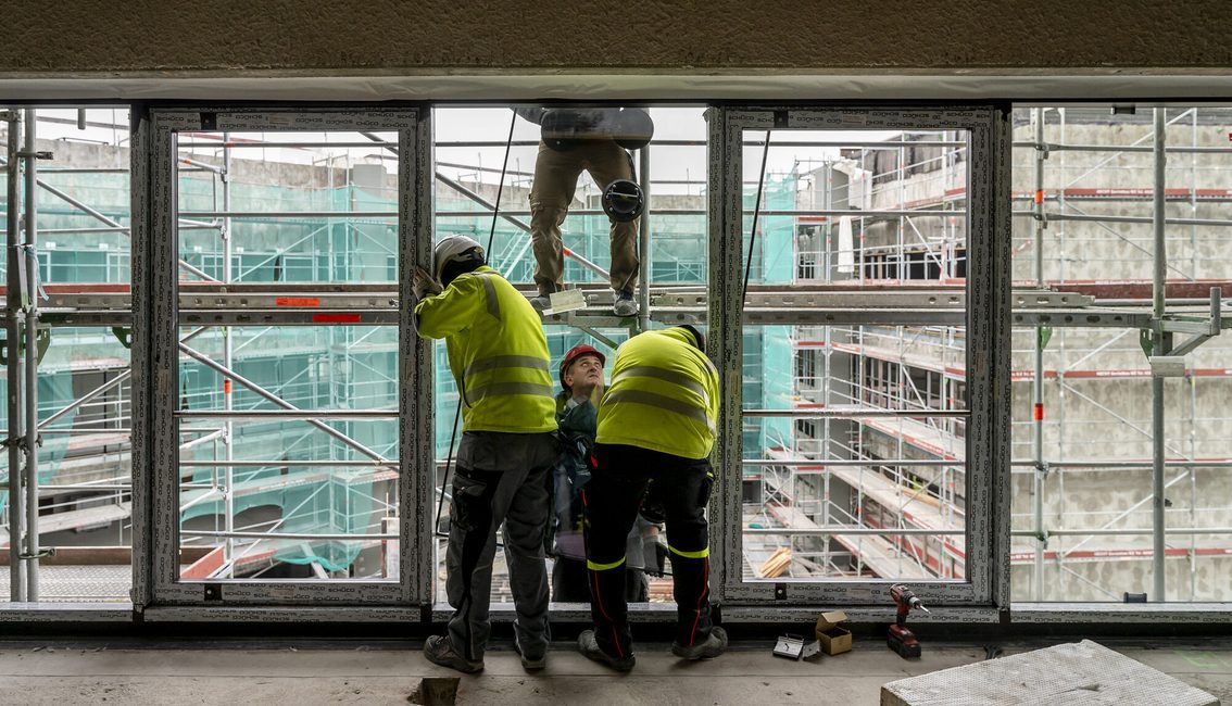 Bauarbeiter arbeiten an der Fensterfront.
