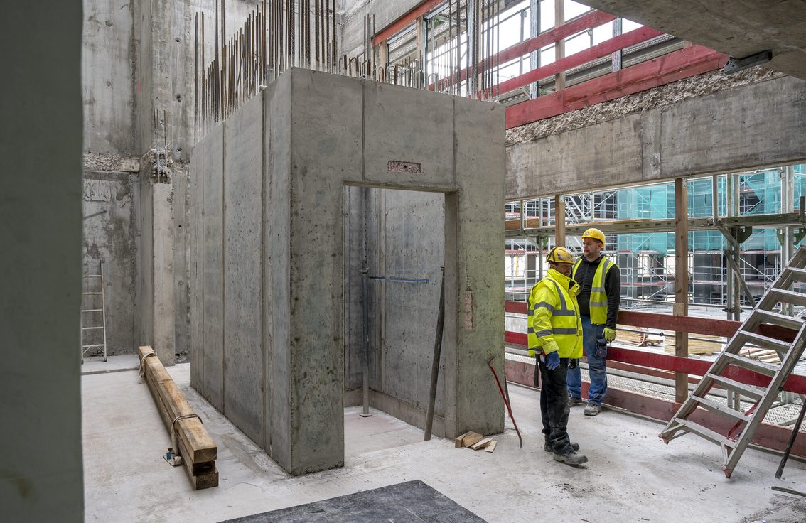Zwei Bauarbeiter stehen in der Rathaus-Baustelle.