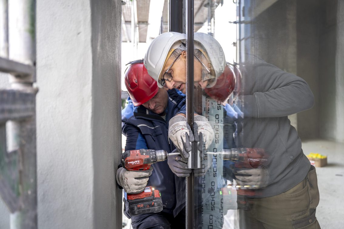 Bauarbeiter setzen Fensterscheiben ein.