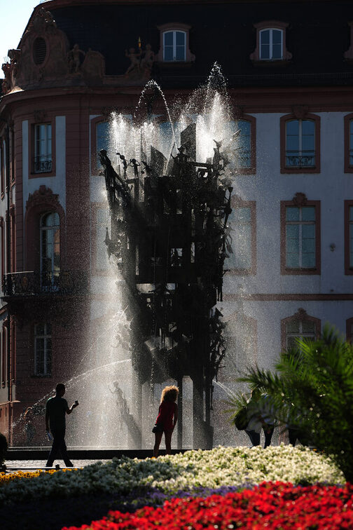 Der Fastnachtsbrunnen mit rotem und weißem Blumenbeet im Vordergrund.