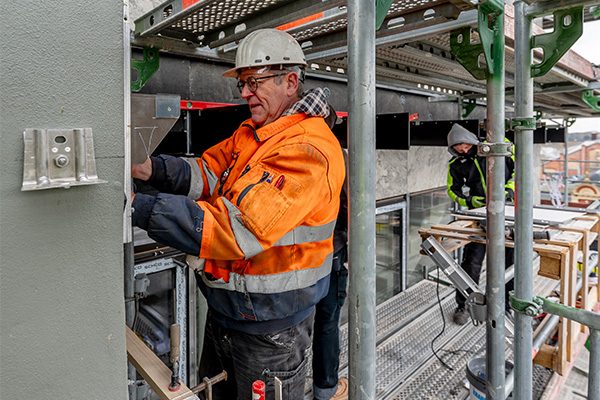 Deux ouvriers se tiennent sur un échafaudage et travaillent sur la façade de l'hôtel de ville.