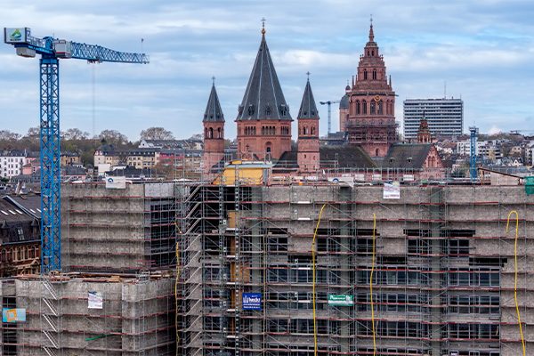 Chantier de l'hôtel de ville avec grue et échafaudage au premier plan, la cathédrale en arrière-plan.