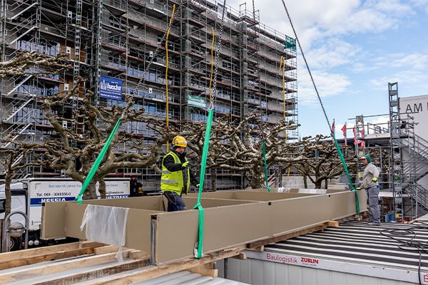 Deux ouvriers du bâtiment font tomber un pare-soleil de la grue.