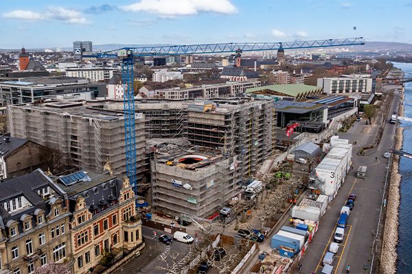 Image de drone du chantier de l'hôtel de ville avec la grue, à droite les conteneurs et la rive du Rhin.