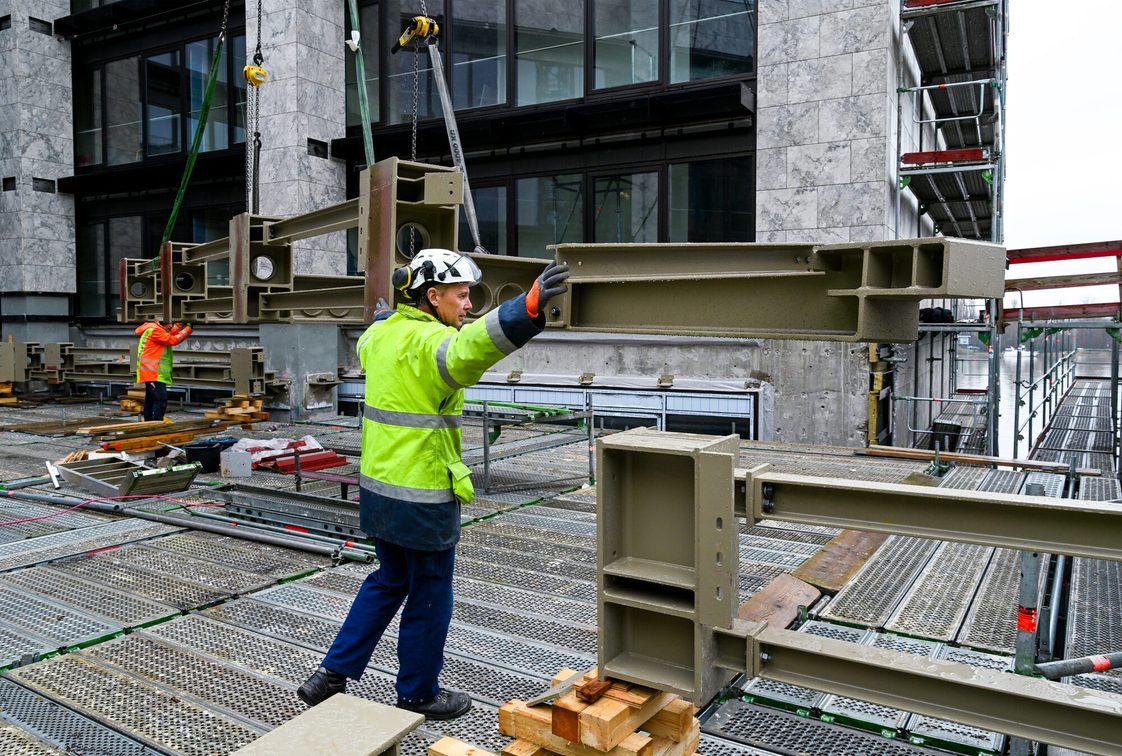 Les ouvriers reçoivent une pièce d'acier sur le chantier de l'hôtel de ville