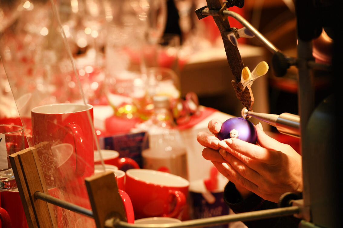 Eine Künstlerin bearbeitet eine Weihnachtskugel