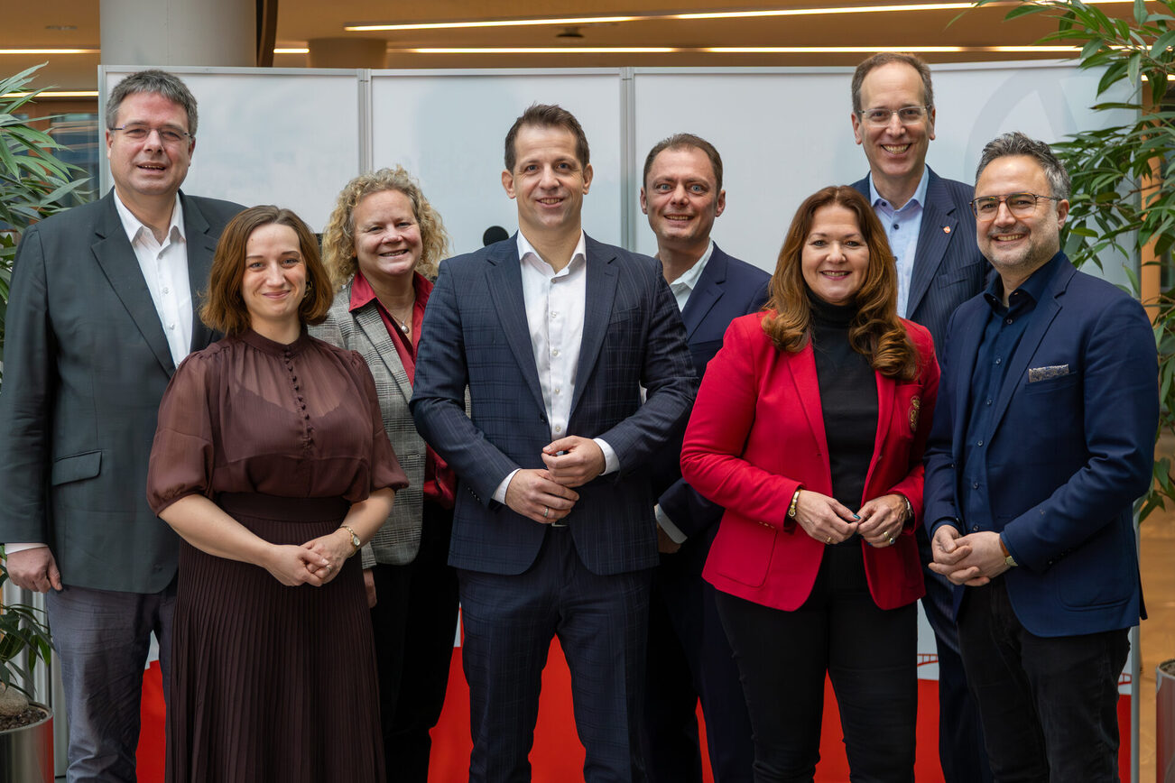 5 Männer und 3 Frauen stehen nebeneinander und lächeln in die Kamera.