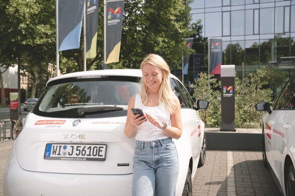 Junge Frau bucht per App ein Carsharing Auto