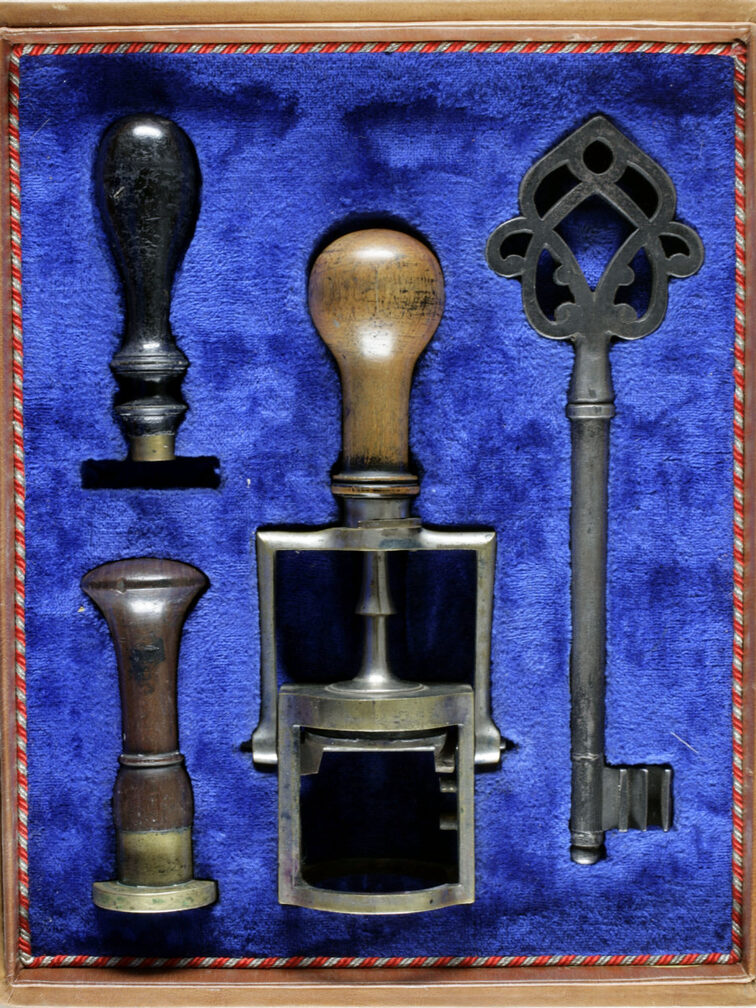 Kästchen mit blauem Samt, darin großer alter Schlüssel und drei Stempel.