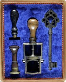 Kästchen mit blauem Samt, darin großer alter Schlüssel und drei Stempel.