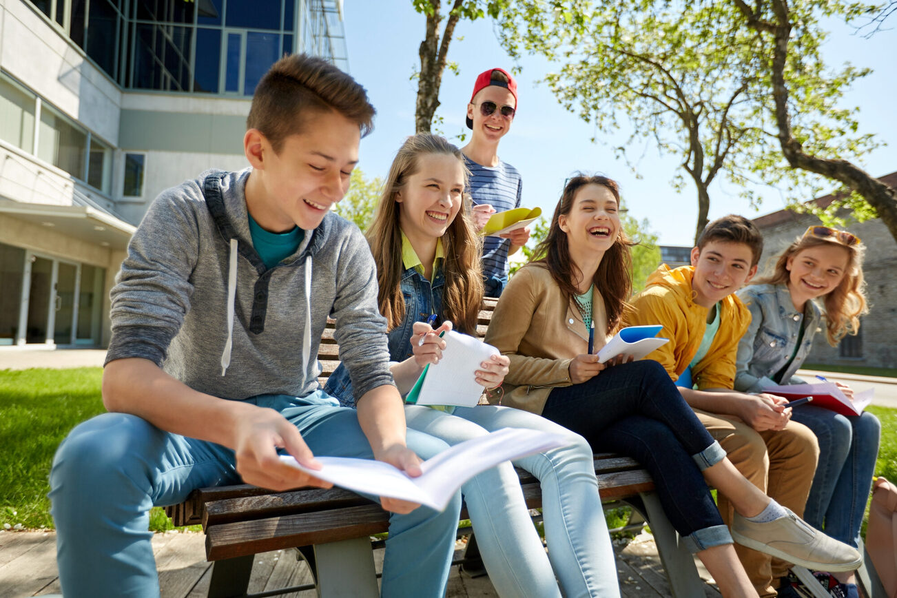 Jugendliche sitzen in der Sonne vor Gebäude