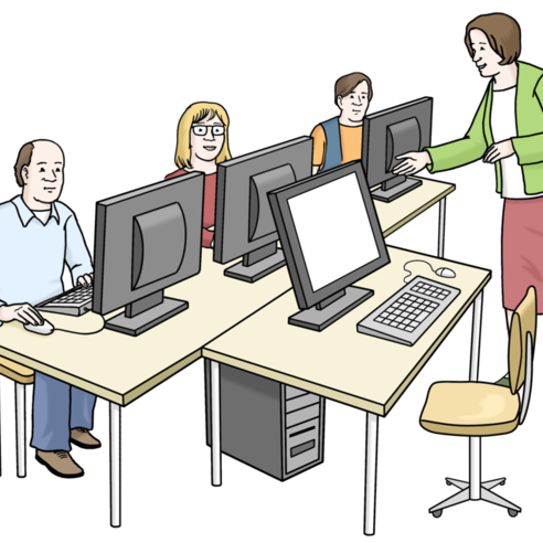 Resim: Dört bilgisayar iş istasyonu, üçünde oturan insanlar, önlerinde durup açıklama yapan bir kadın.