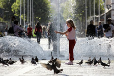 Ein Mädchen füttert vor dem Höfchenbrunnen Tauben