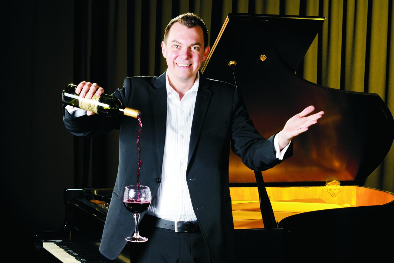 Zauberer Oliver de Luca schenkt Rotwein in ein schwebendes Glas ein.