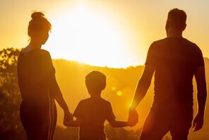 Eine Familie, bestehend aus Mann, Frau und Kind vor einem Sonnenuntergang &copy; Pixabay