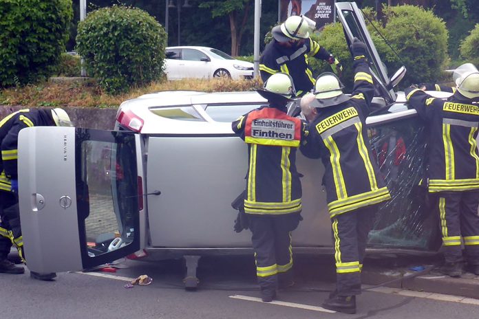 Rettungskräfte arbeiten an dem auf der Seite liegenden Unfallfahrzeug.