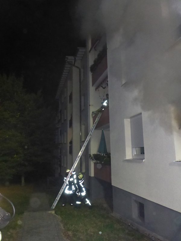 Einsatzkräfte stützen eine Leiter am Brandobjekt.