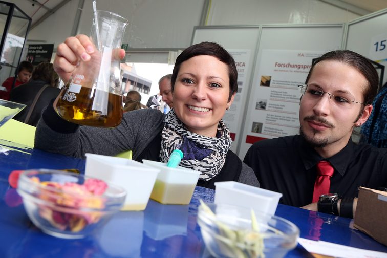 Une jeune femme tient en l'air un flacon de liquide