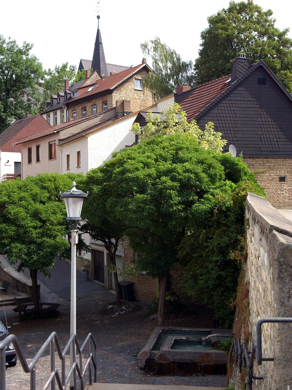 Vistas idílicas de la iglesia, la pequeña fuente y las casas de Hechtsheim desde una escalera