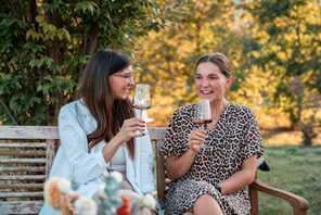 Zwei Frauen sitzen mit einem Glas Wein auf einer Bank. © Weingut Wasem Doppelstück